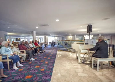 Senior citizens listening to a pianist at the Garden Villas North