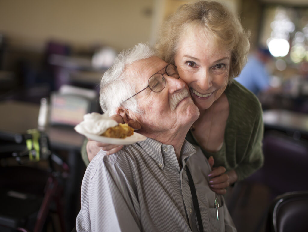 Senior woman hugging senior man, smiling